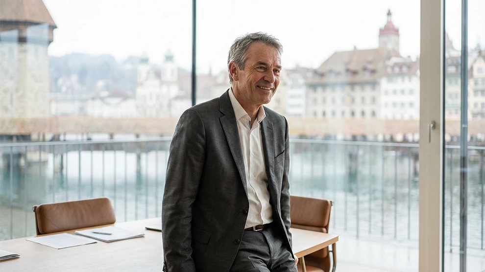 Luzern Job 1 Recruiting-Plattform Schweiz: Mann im Büro mit Blick auf Luzern, Jobs in Treuhand, Buchhaltung, Rechnungswesen.