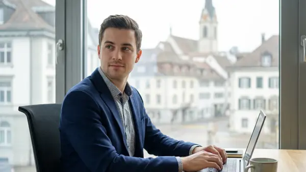 Mann in Büro am Laptop, Blick nach draußen. Jobsuche in Treuhand, Buchhaltung und Rechnungswesen in der Schweiz.